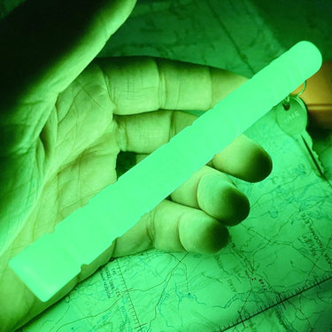 Hand holding a glowing green, ribbed nylon Glo-Baton Kubaton over a map.