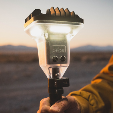 Hand holding a portable light source with a desert landscape in the background