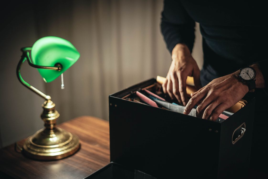 A person organizing important documents in a file box