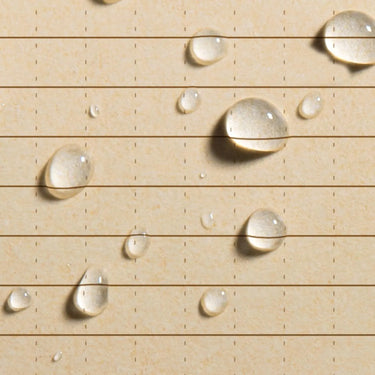 Close-up of tan Rite in the Rain all-weather paper with universal pattern and water droplets.