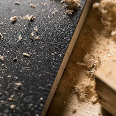 Close-up of a black Rite in the Rain 3x5 top spiral notebook cover with wood shavings.