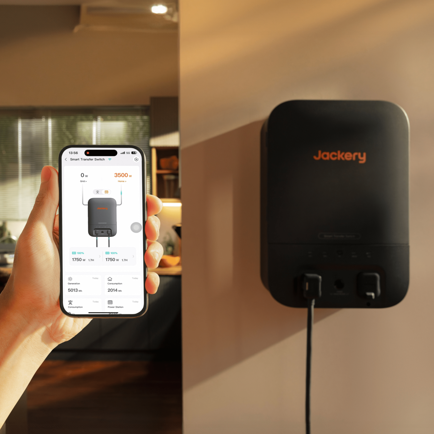 Black Jackery Smart Transfer Switch mounted on a wall, with a hand holding a phone displaying its app interface.