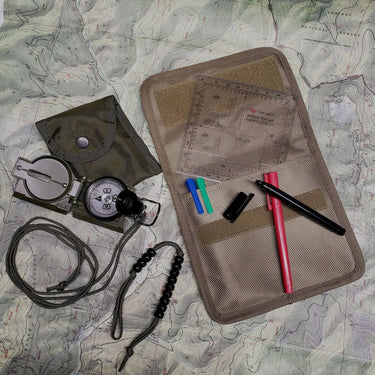 Green compass navigation kit with protractor, pace beads, markers, and pouch on a topographic map.