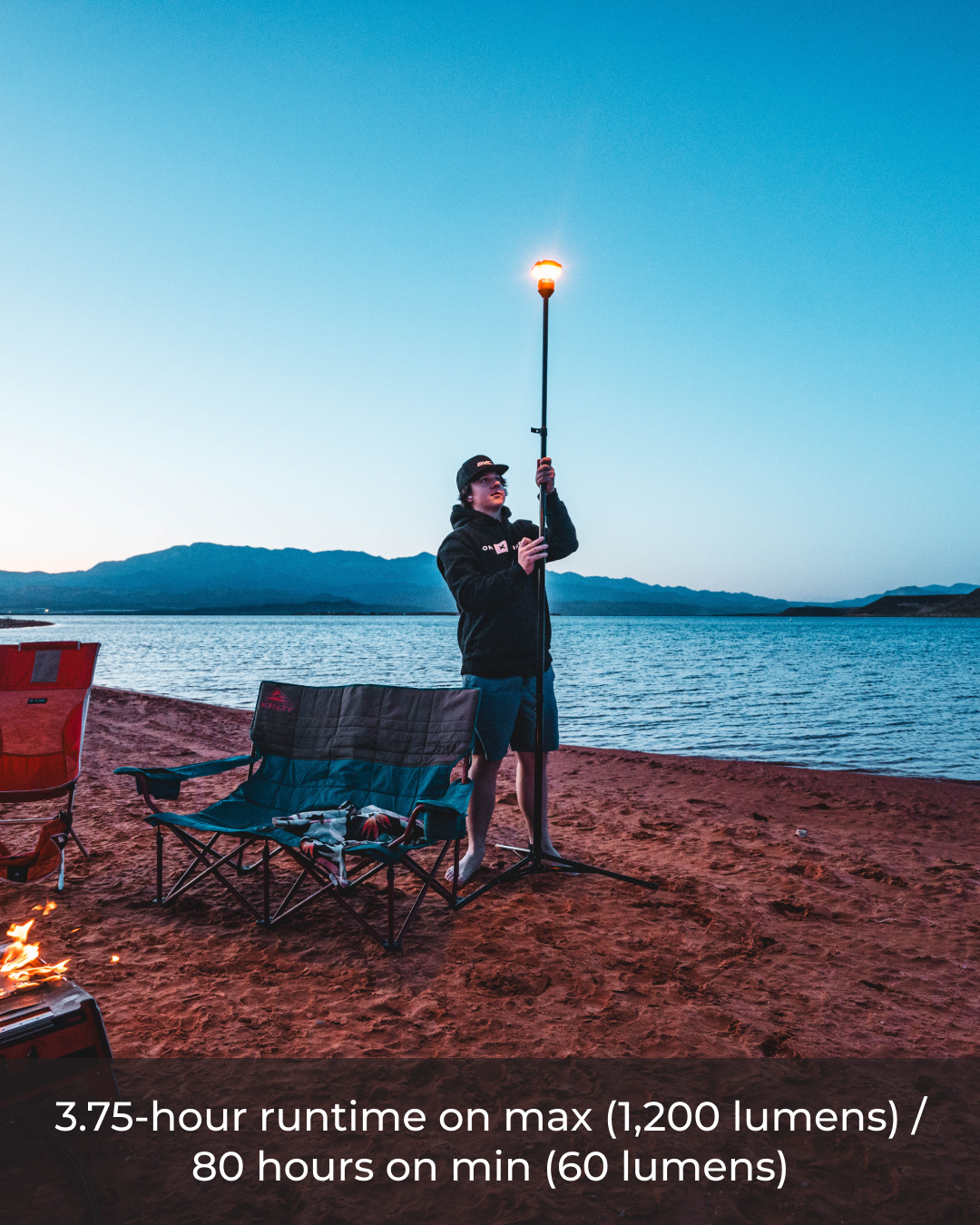 Man adjusting a black Devos LightRanger 1200 with an orange glow on a sandy beach at dusk.