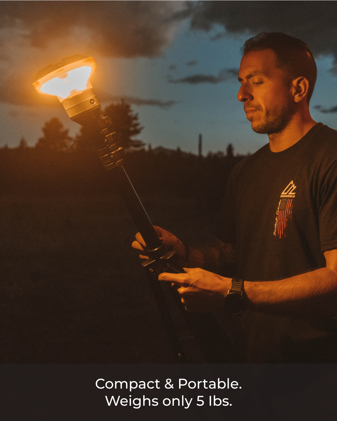 Man adjusting a glowing Devos LightRanger 1200, a portable black telescoping light pole, at dusk.