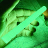 Hand holding a glowing green, ribbed nylon Glo-Baton Kubaton over a map.