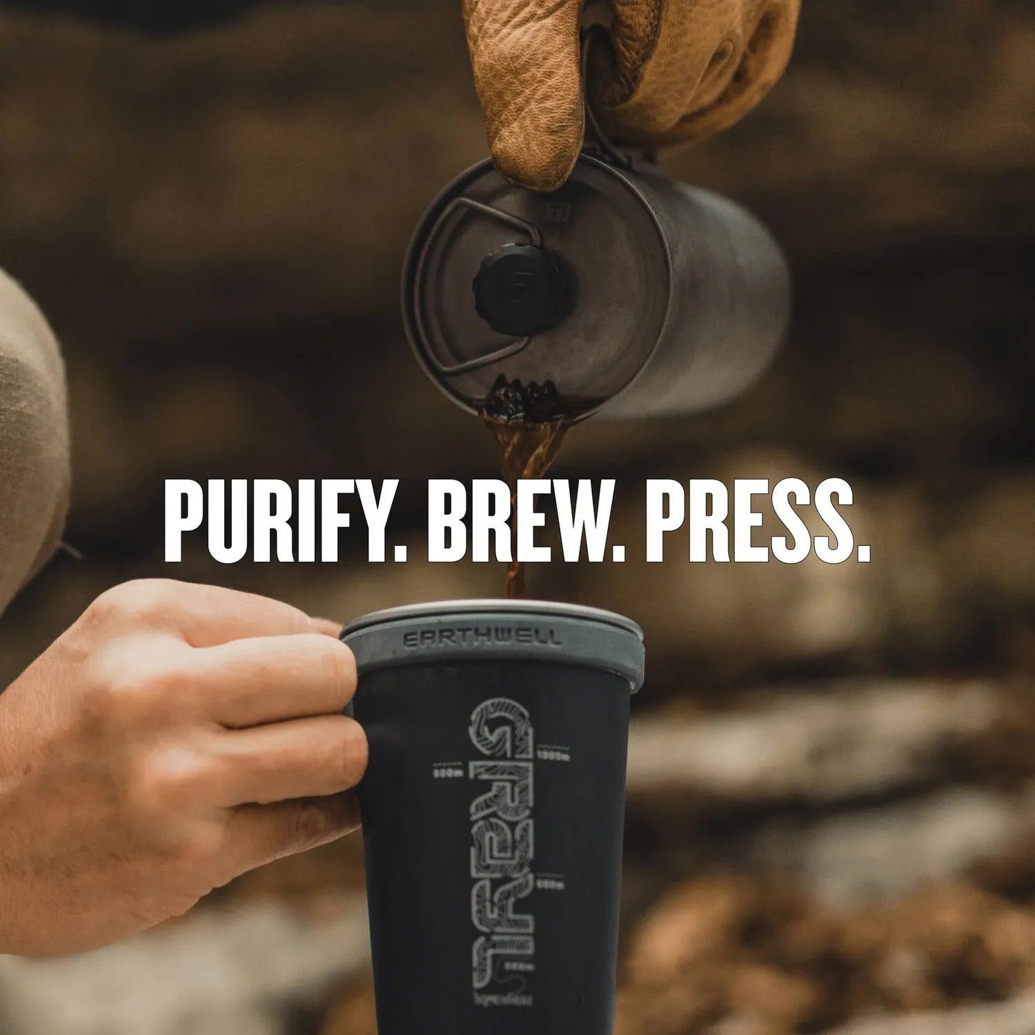 Hand pouring dark coffee from a titanium Grayl GeoPress into a black mug.