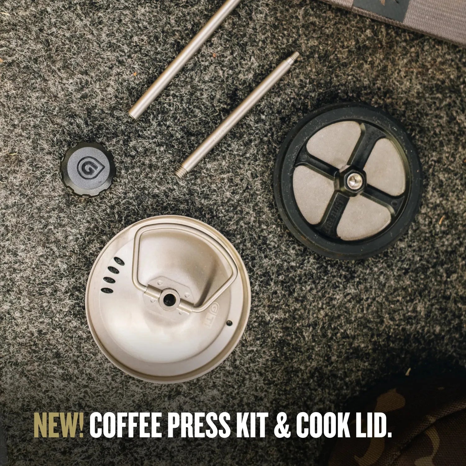 Grayl GeoPress® Ti Coffee Press kit components: titanium filter, plunger rods, and black cap on a dark gray surface.