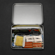 Small metal survival tin with various items including fishing line and tools on a dark background