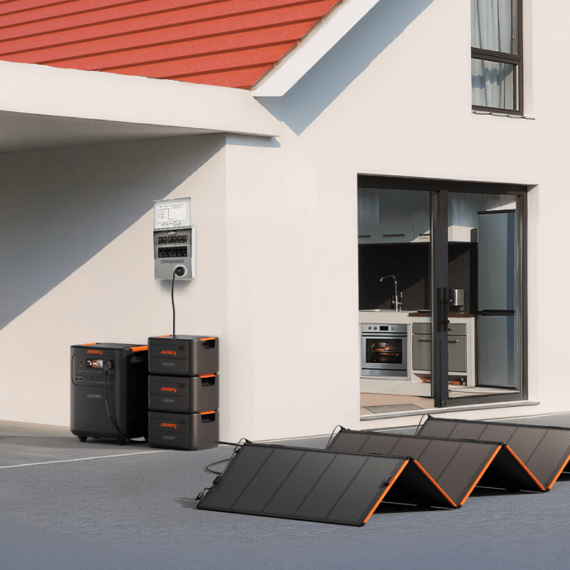 Jackery HomePower 3600 Plus system with stacked battery packs and solar panels outside a modern white house.
