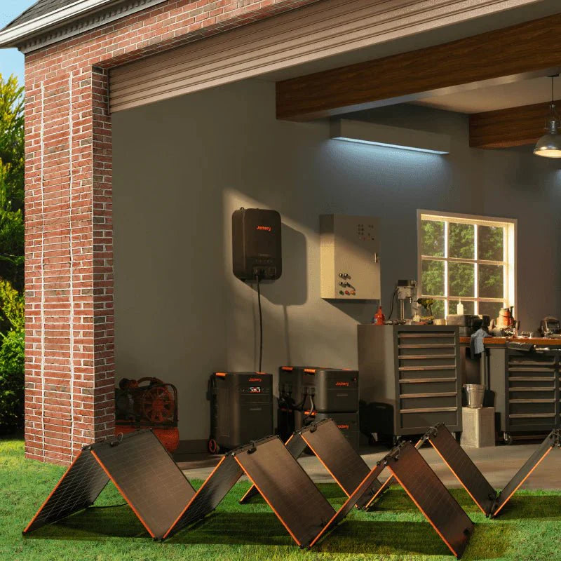 Jackery Explorer 5000 Plus power station and solar panels outside a garage, charging home appliances.