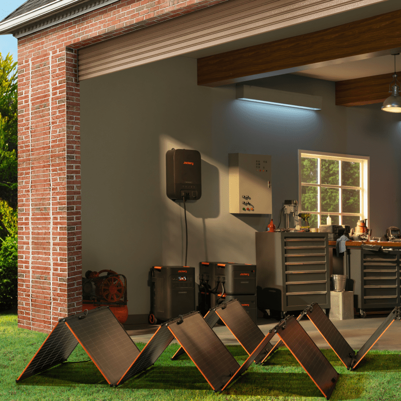 Jackery Explorer 5000 Plus Double Kit with multiple black solar panels on green grass, next to a garage.