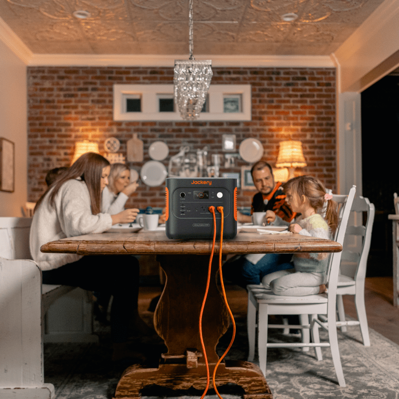 Jackery Solar Generator 2000 v2, a compact black and orange portable power station, on a dining table.