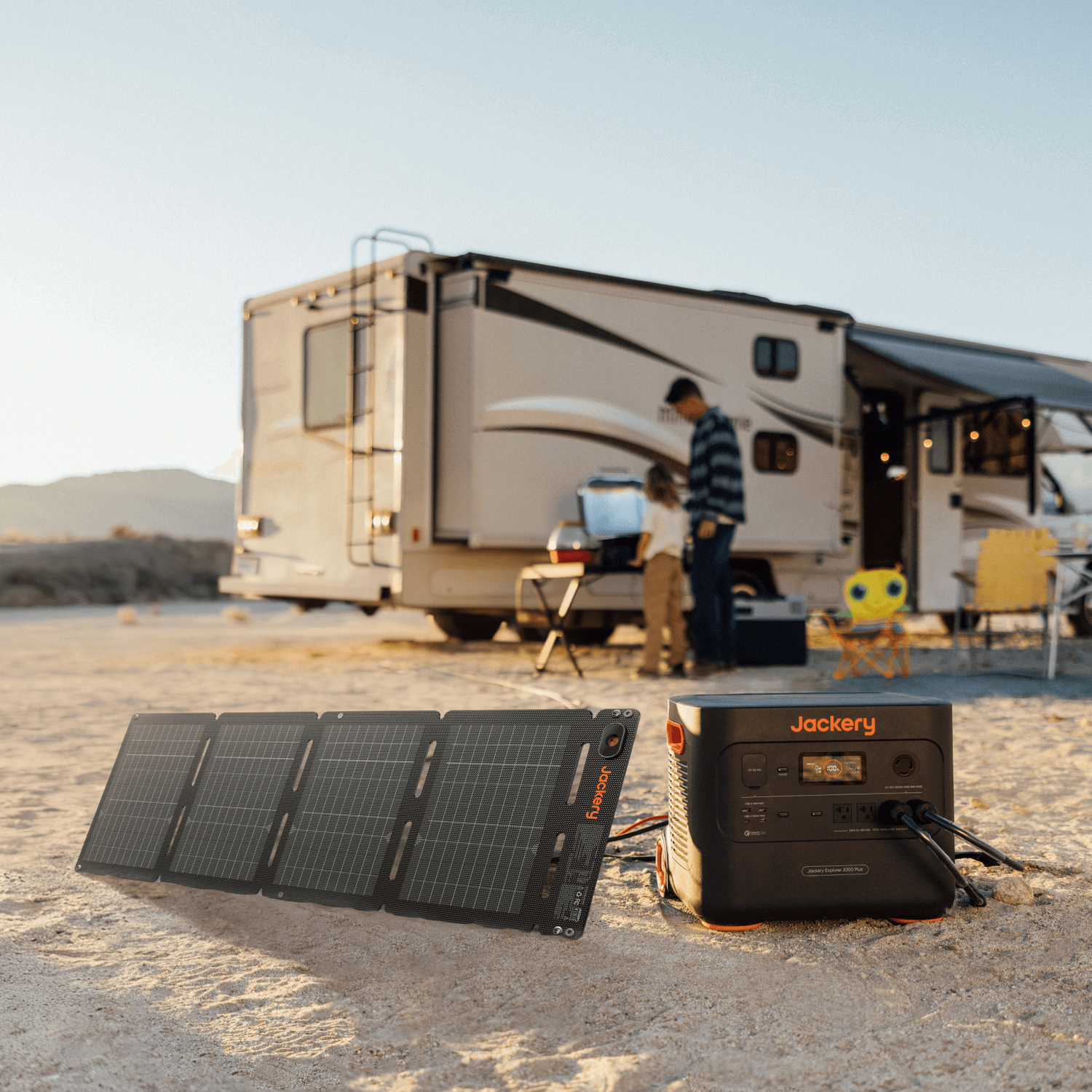 Jackery SolarSaga 40 Air portable solar panel and Explorer power station on sand, RV in background.