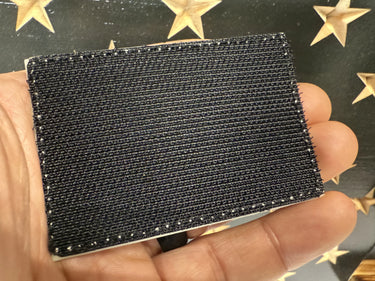 Hand holding a black silicone Maratac Topography Glow Patch with hook Velcro backing.