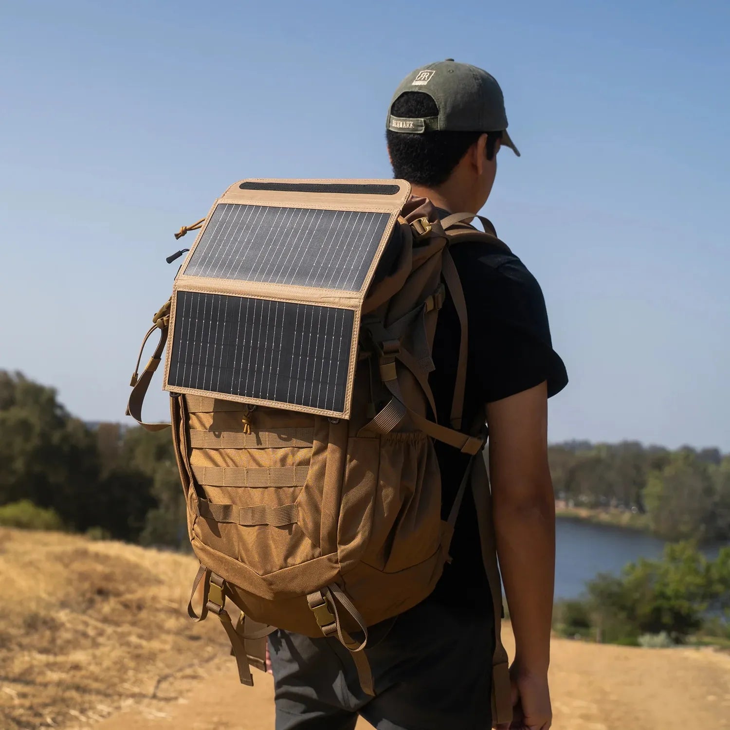 NESTOUT 2-Panel Solar Charger V2 attached to a tan backpack, worn by a person outdoors.