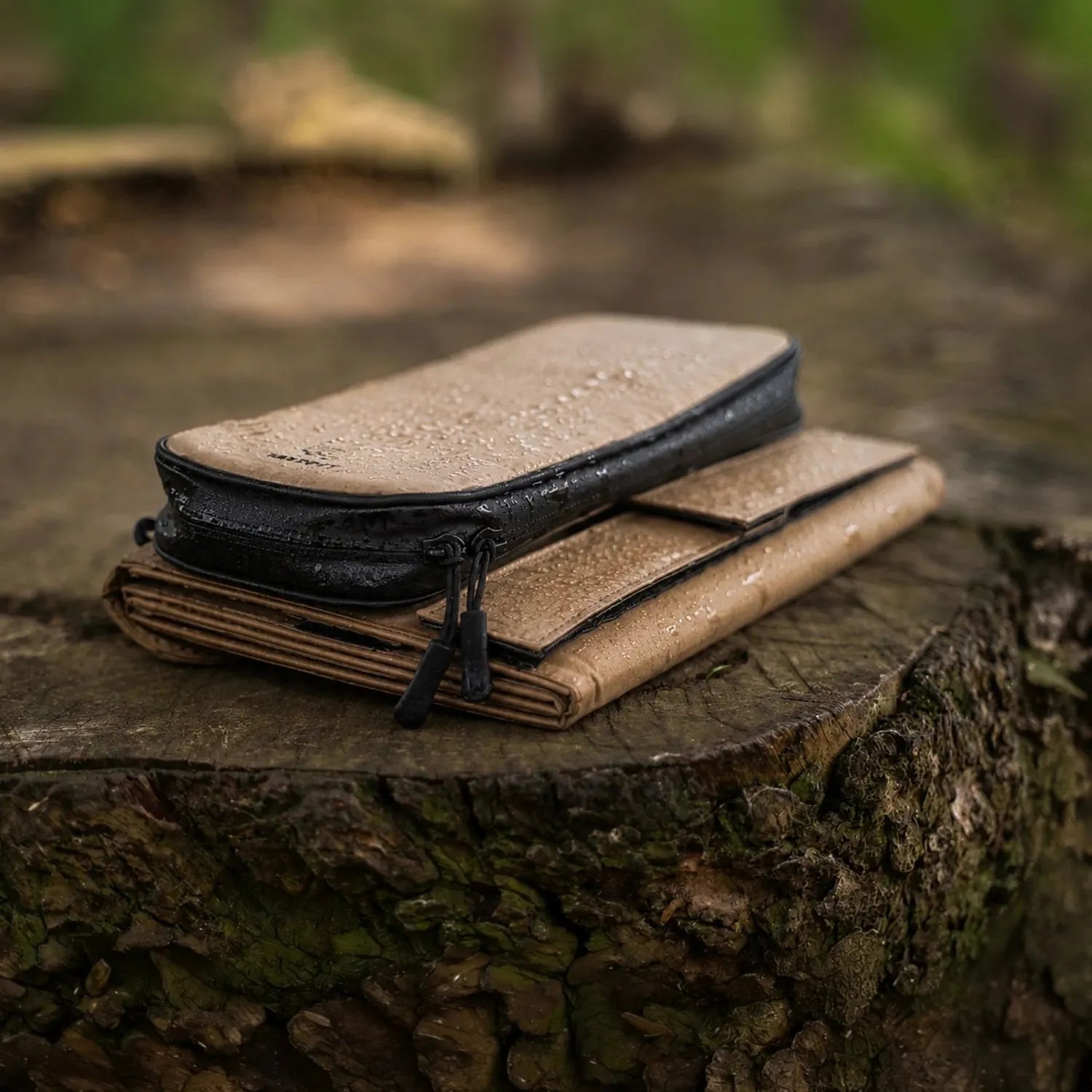 NESTOUT 2-Panel Solar Charger V2, folded, tan and black, with a matching zippered case on a tree stump.