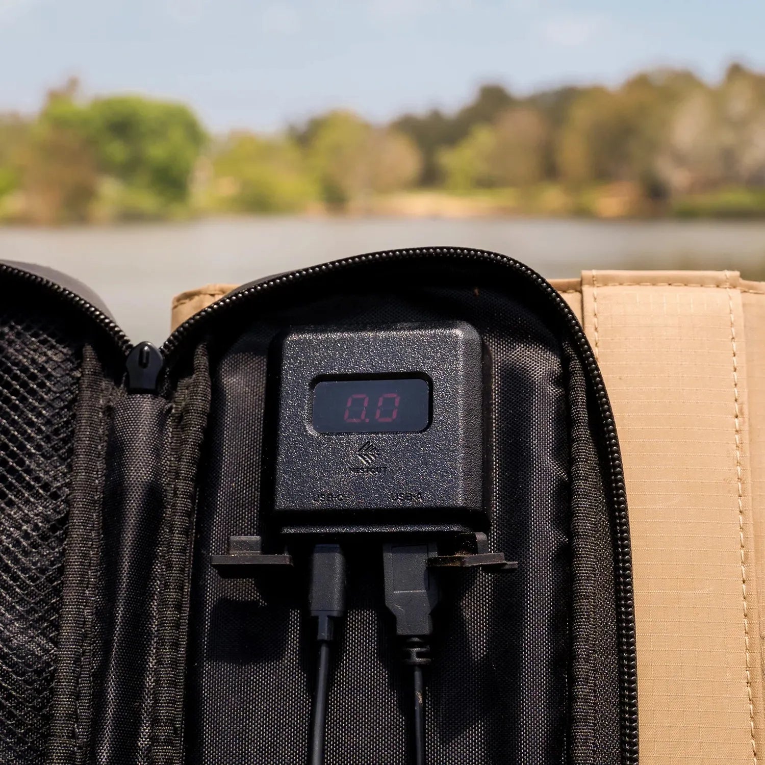 NESTOUT 4 Panel Solar Charger V2's black digital power meter with USB ports, nestled in a tan and black case.