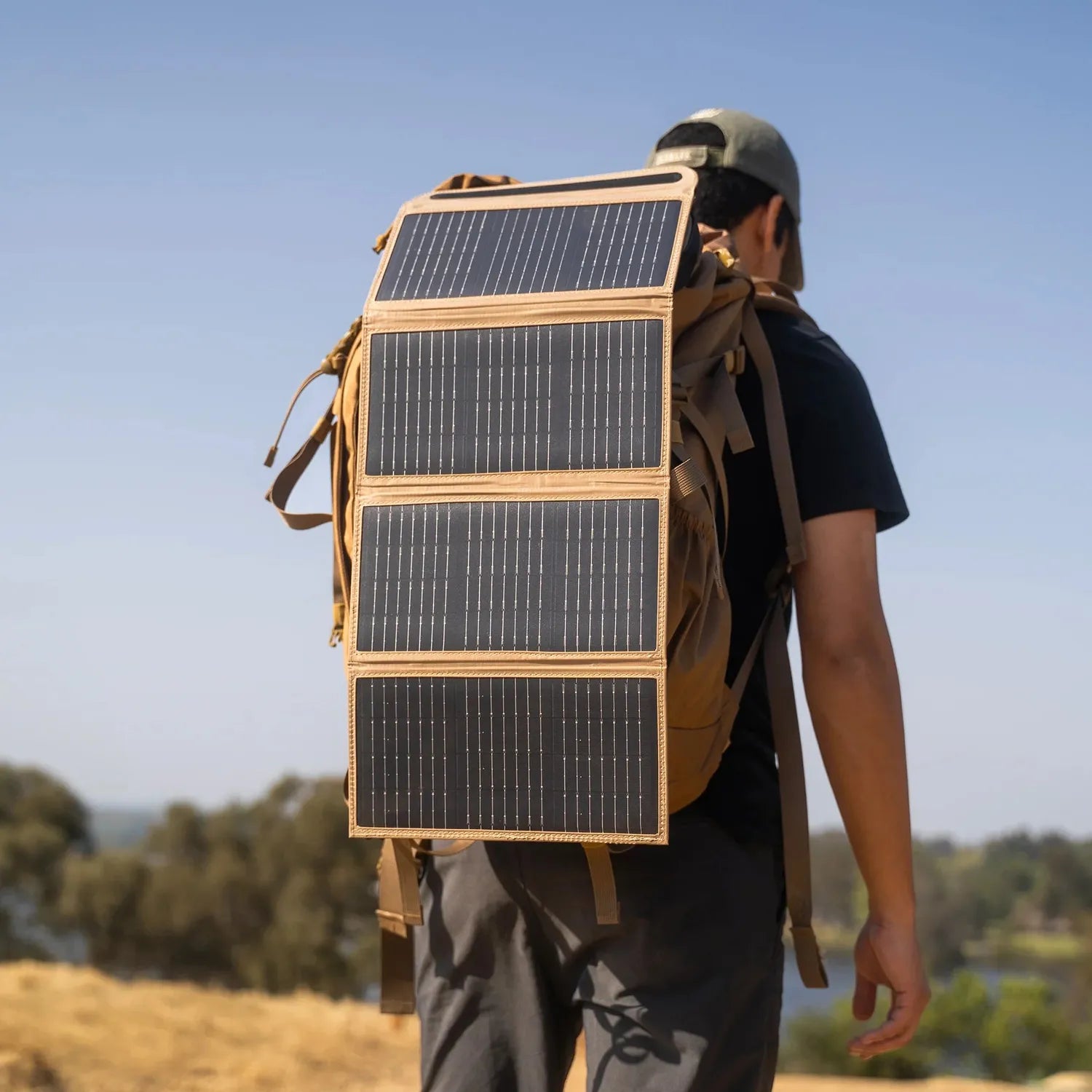 NESTOUT 4 Panel Solar Charger V2, tan and black, attached to a backpack on a person outdoors.