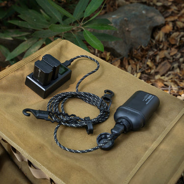 Black Tetoron braided outdoor USB-A to USB-C charging cable with a cap and hook, connected to a battery charger.