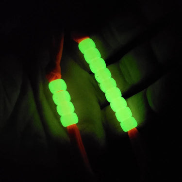 Glow-in-the-dark phosphorescent pace counter beads on an orange cord, visible in low light.