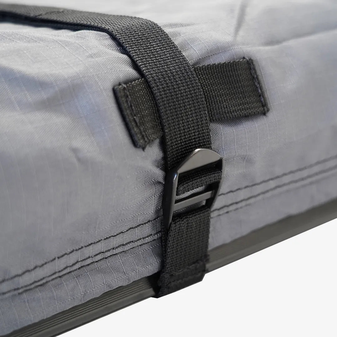 Close-up of a light gray ripstop protective cover with a black strap and buckle securing it.