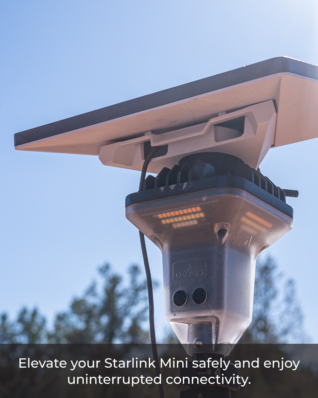 Close-up of a gray Starlink Mini mounted on a LightRanger pole against a bright blue sky.