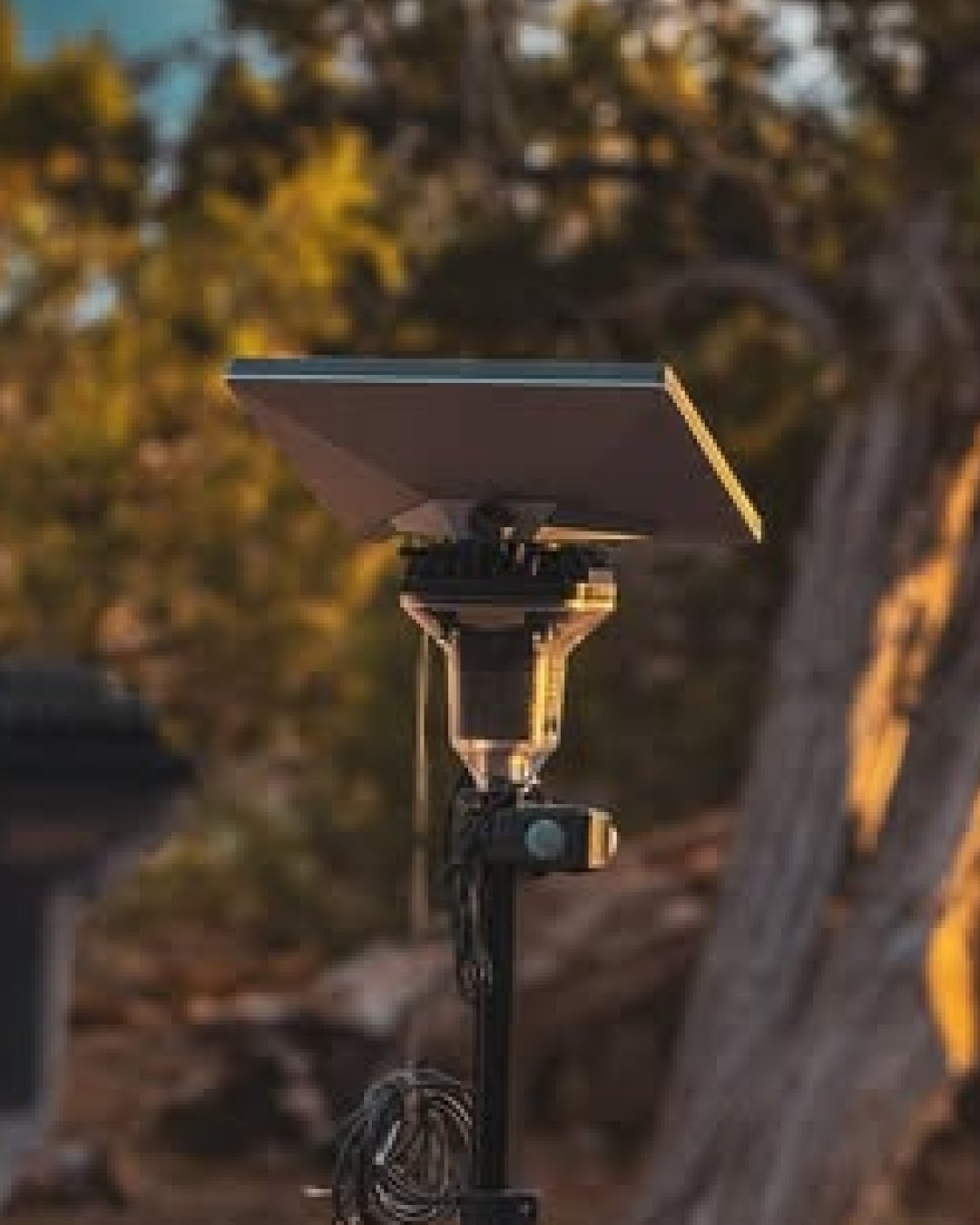 Dark gray Starlink Mini satellite dish mounted on a black LightRanger pole, with a blurred outdoor background.