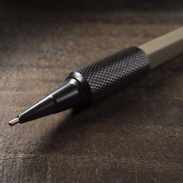 FDE mechanical pencil with a black knurled grip and 1.3mm lead, on a wooden surface.