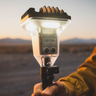 Hand holding a portable light source with a desert landscape in the background