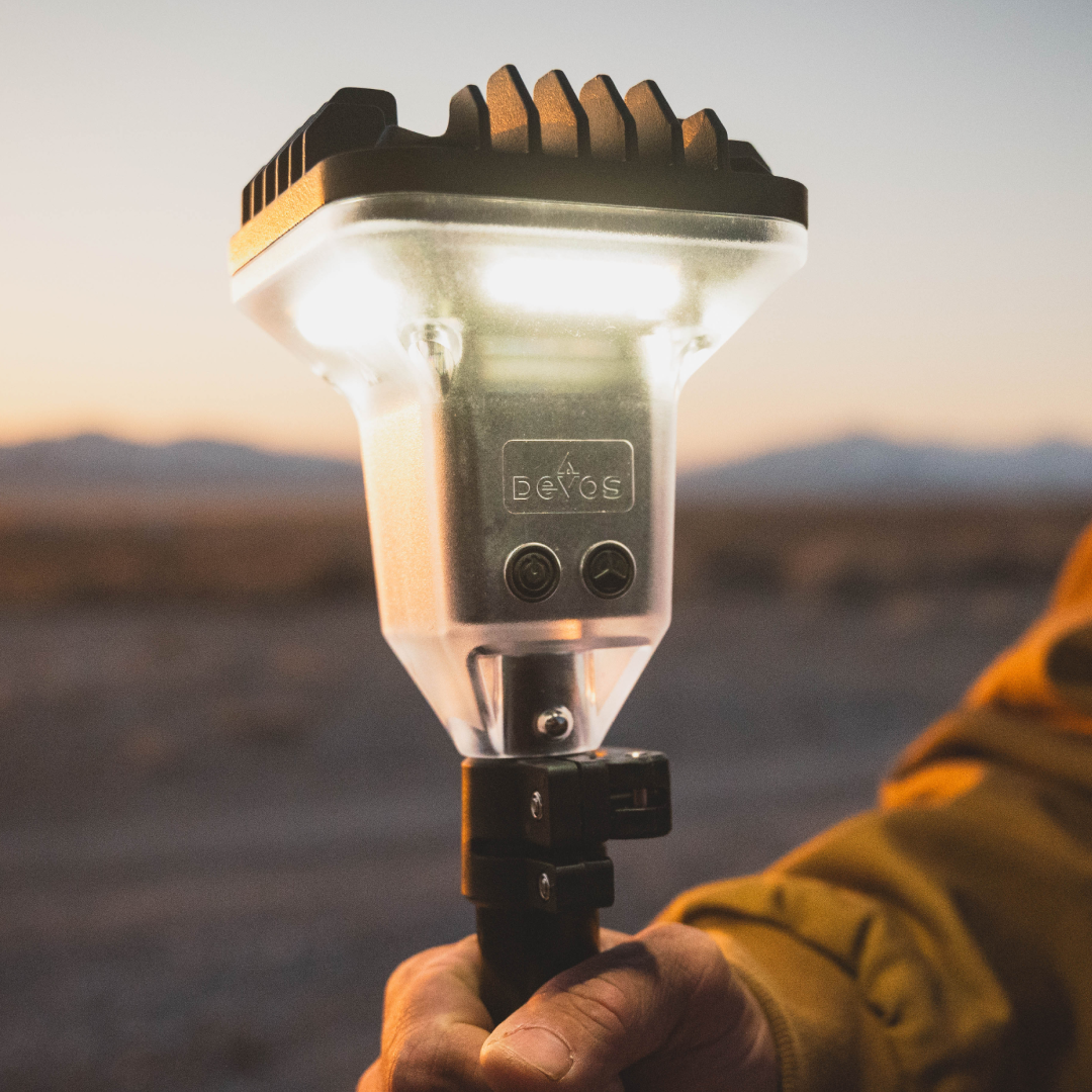 Hand holding a portable light source with a desert landscape in the background